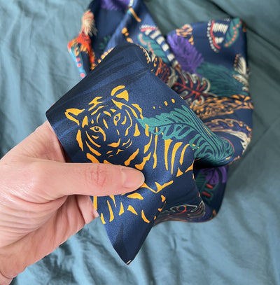 25 momme silk tiger print fabric being rubbed by a thumb