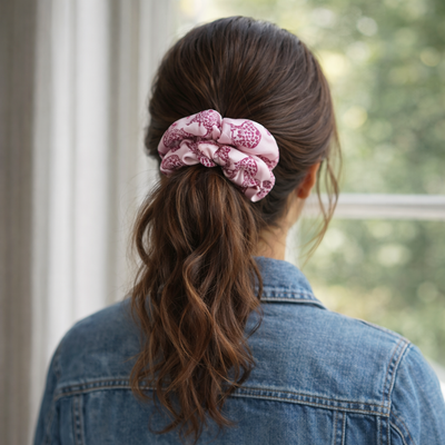 MYRN pink leopard print silk scrunchie in a ladies hair by a window