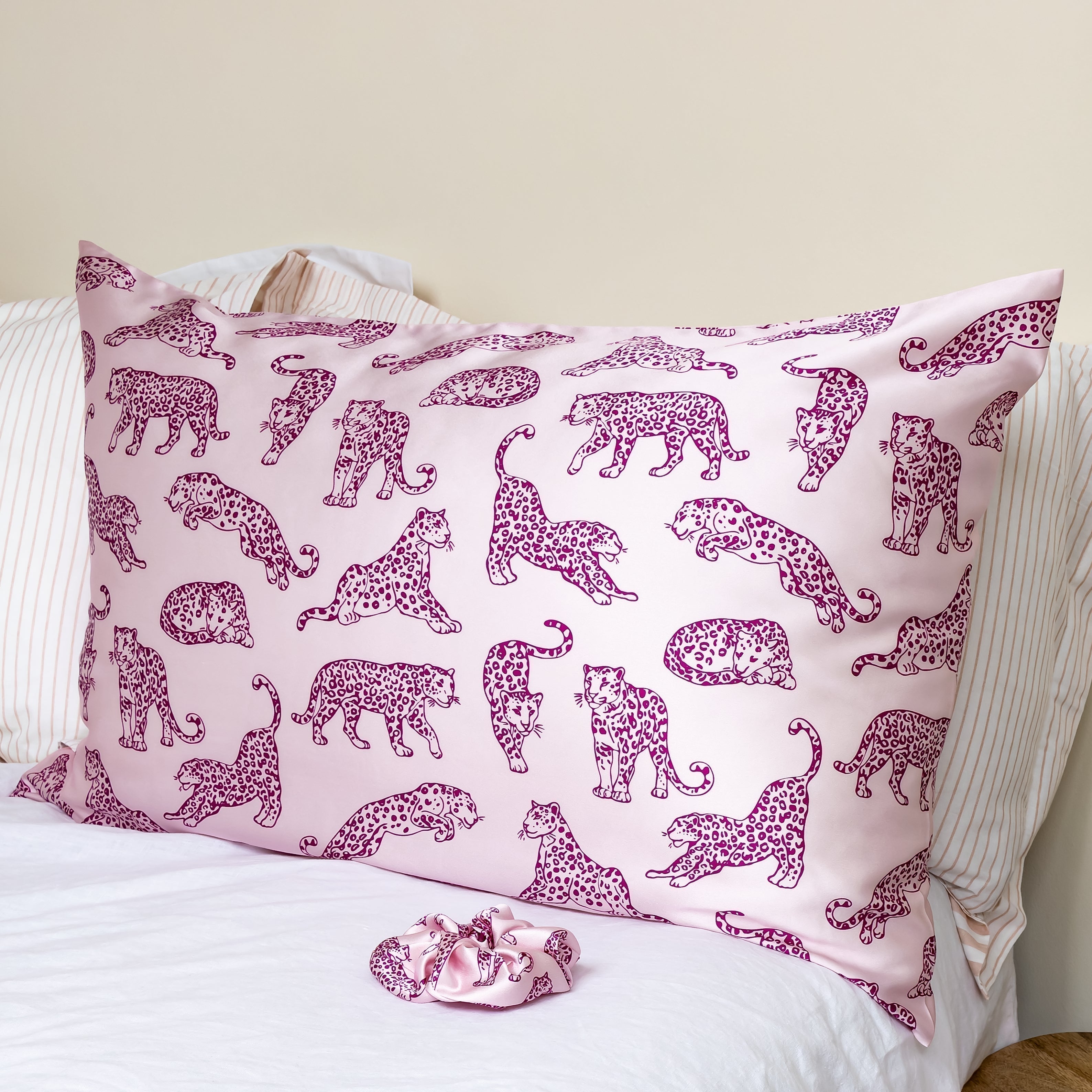MYRN Silk pink leopard printed silk pillowcase and matching scrunchie on a bed