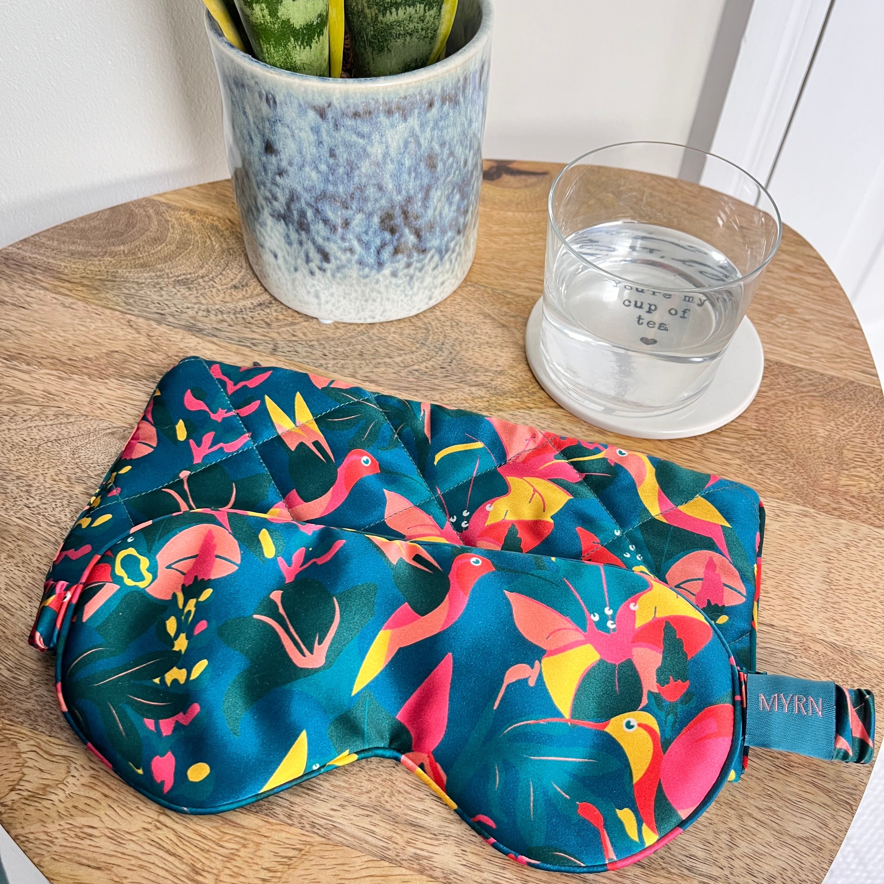 Lively Hummingbird printed silk mask and travel case on a bedside table
