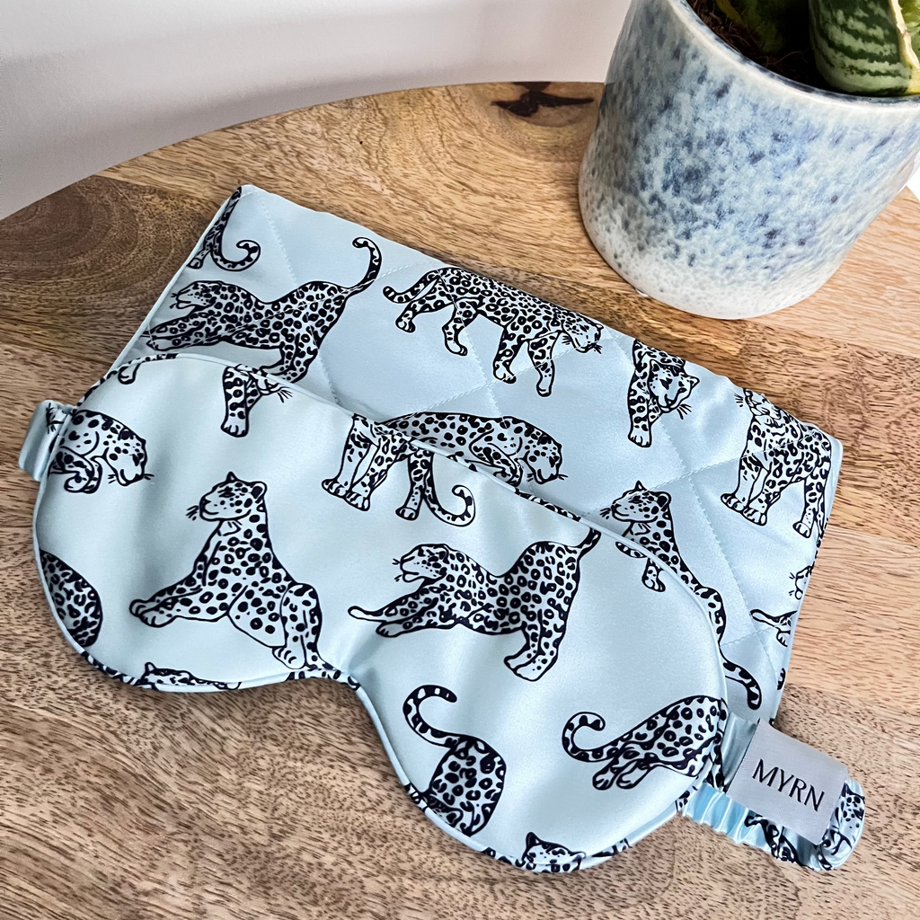 MRN Blue Leopard printed silk eye mask and travel case on a bedside table