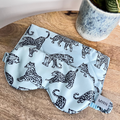 MRN Blue Leopard printed silk eye mask and travel case on a bedside table