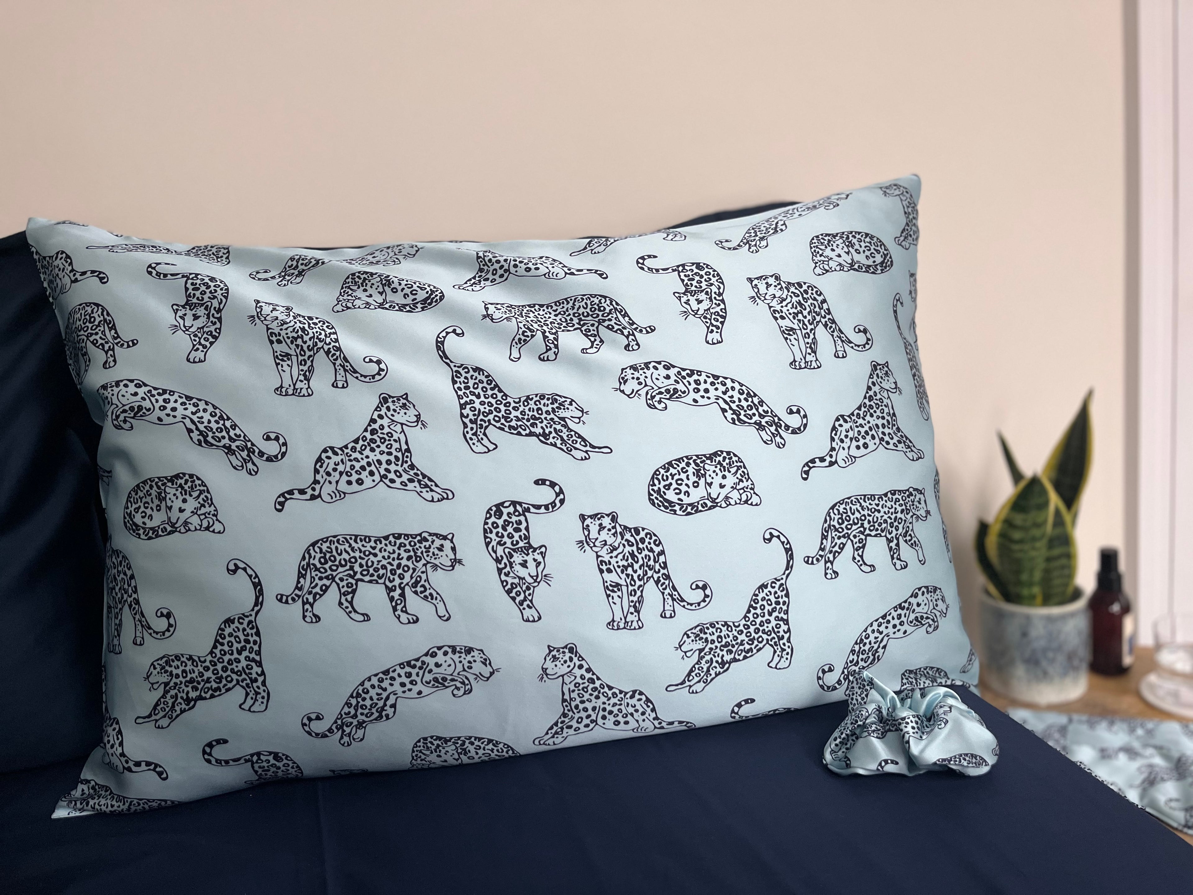 MYRN Blue Leopard Printed silk pillowcase and matching scrunchie on a bed