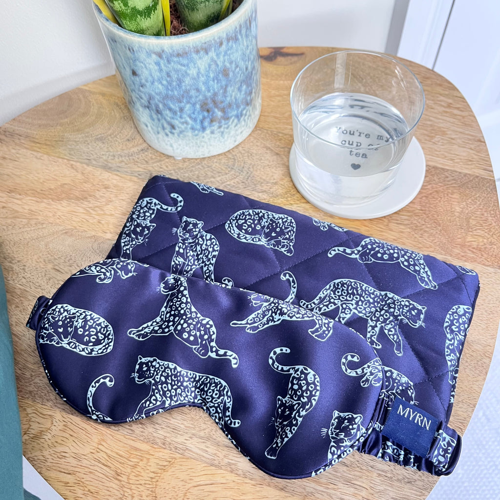 MYRN Midnight Blue Leopard Printed Silk eye mask with matching travel case on a bedside table