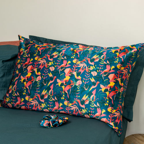 Hummingbird printed silk pillowcase with a matching scrunchie on a bed.