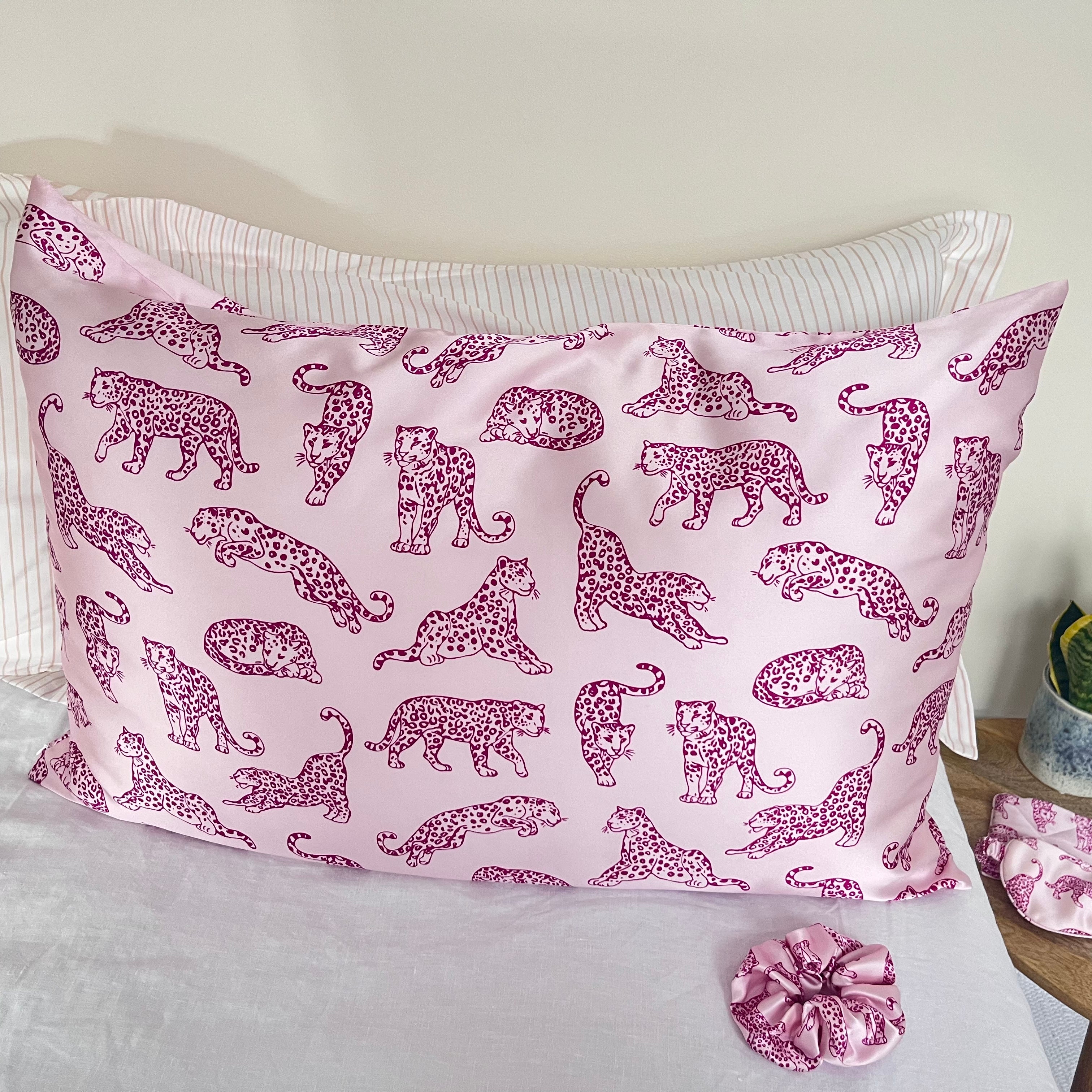 MYRN Silk Pink Leopard printed silk pillowcase and silk scrunchie on a bed.