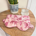 MYRN Silk Pink Leopard printed silk eye mask and travel case on a bedside table